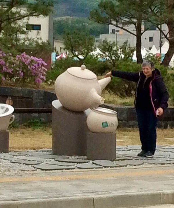 Sylvie Robert devant une sculpture de théière géante